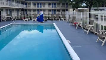A swimming pool with lounge chairs and a fenced deck area.