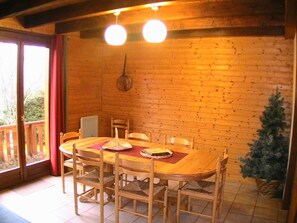 A wooden dining table with chairs, a hanging light fixture, and a Christmas tree. - 3-Star Chalet in Gérardmer with 3 Bedrooms (Gérardmer)