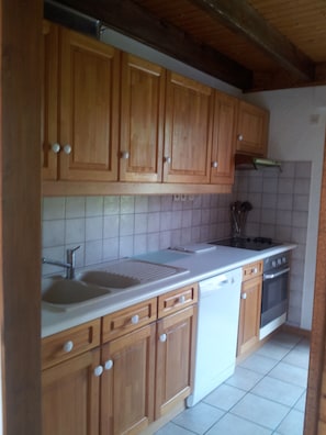A kitchen with wooden cabinets, a white countertop, a sink, a stove, and a dishwasher. - 3-Star Chalet in Gérardmer with 3 Bedrooms (Gérardmer)