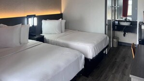 Quarto de hotel com duas camas, uma escrivaninha e banheiro.