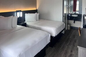 Une chambre d’hôtel avec deux lits, un bureau et une salle de bain.