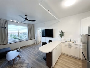 Una cocina moderna con una isla integrada, un televisor de pantalla plana y una zona de comedor con banco.