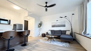 Een moderne woonkamer met een bank, een bijzettafeltje en twee barkrukken.