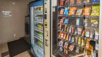 Área com máquina de vendas automática, bebedouro e máquinas de venda de lanches.