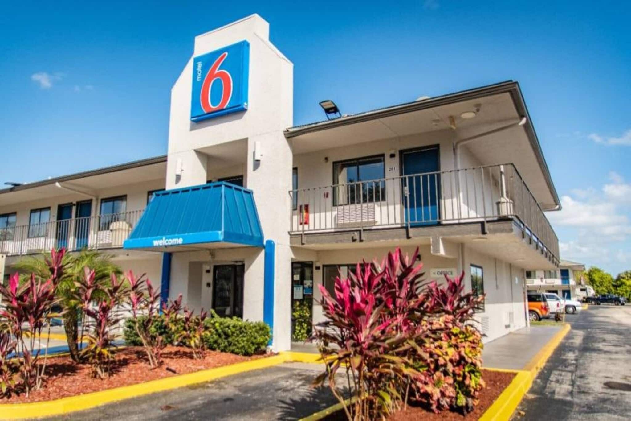 Een motel met een groot '6' bord, een blauw luifel en een balkon op de tweede verdieping.
