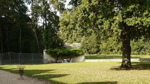 A park with a gravel path, a metal bench, and a stone wall. - A gorgeous, cozy vacation rental, perfect for families, with a garden, near Disney and Paris. The workshop. (Aulnoy)