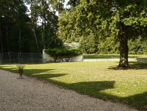 A park with a gravel path, a metal bench, and a stone wall. - A gorgeous, cozy vacation rental, perfect for families, with a garden, near Disney and Paris. The workshop. (Aulnoy)