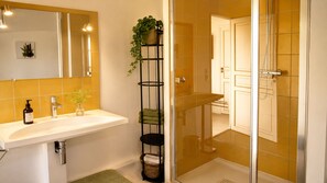 A bathroom with a white sink, a mirror, a potted plant, and a shower area. - A gorgeous, cozy vacation rental, perfect for families, with a garden, near Disney and Paris. The workshop. (Aulnoy)