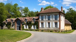 A large, multi-story house with a driveway and a well-maintained lawn. - A gorgeous, cozy vacation rental, perfect for families, with a garden, near Disney and Paris. The workshop. (Aulnoy)