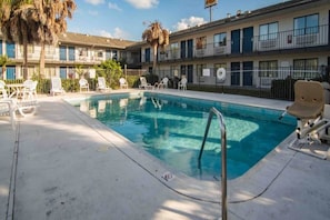 A swimming pool with lounge chairs and a building with balconies in the background. - Motel 6 Ft. Pierce, Fl_1 Queen Bed | Ada (Fort Pierce)