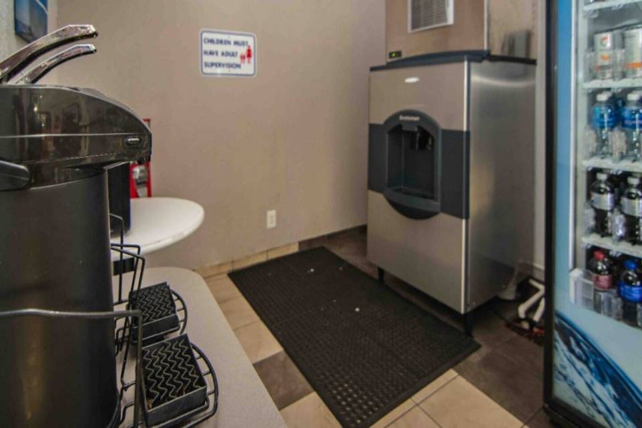 Una kitchenette equipada con un lavamanos, estufa y dispensador de agua.