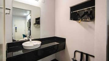 A bathroom with a white sink, a mirror, and a black towel rack.