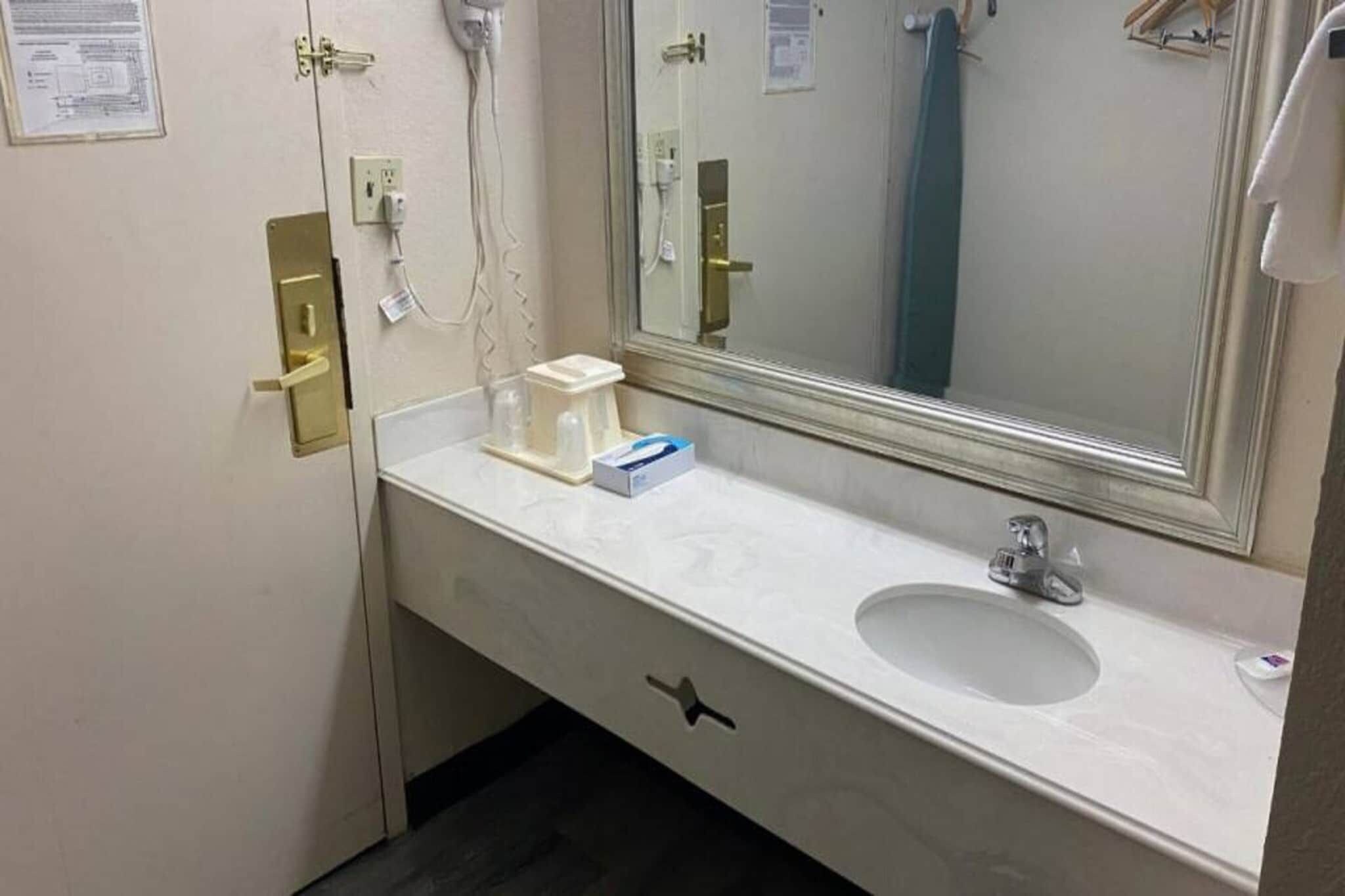Une salle de bain d’hôtel avec un lavabo blanc, un miroir et un porte-serviettes.