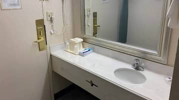Une salle de bain d’hôtel avec un lavabo blanc, un miroir et un porte-serviettes.