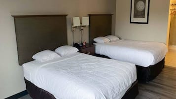 Ett hotellrum med två separata sängar, ett nattduksbord, en vägglampa och en inramad tavla.
