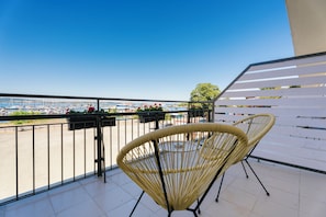 A balcony with two wicker chairs, a view of a marina, and a clear sky. - Hotel Sozopol 99 (Sozopol)