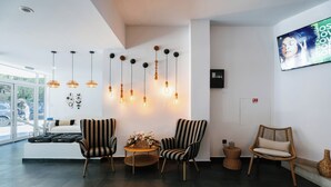 Una sala de estar moderna con sillas a rayas, una mesa redonda de madera y lámparas colgantes.