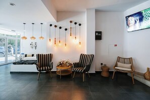 Una sala de estar moderna con sillas a rayas, una mesa redonda de madera y lámparas colgantes.