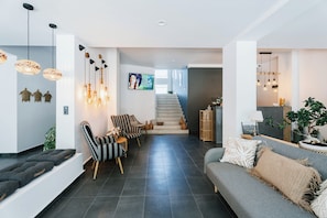 A modern living room with a staircase, a sofa, and a dining area. - Hotel Sozopol 99 (Sozopol)