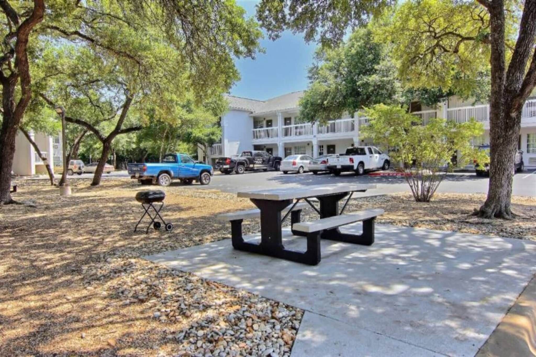 Un tavolo da picnic in un parco con alberi e un edificio sullo sfondo.