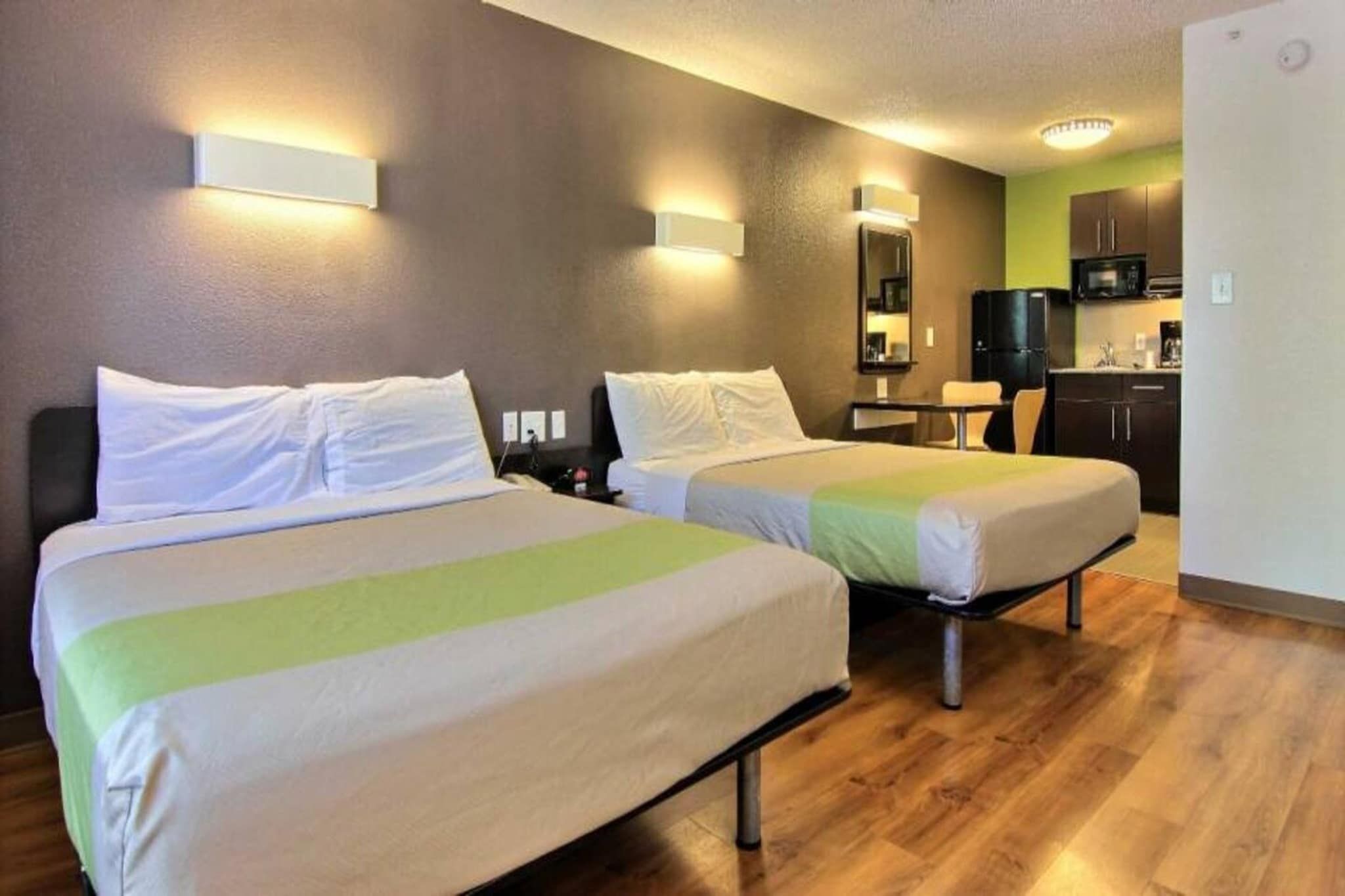 Una camera d'albergo con due letti, un angolo cottura e un bagno.