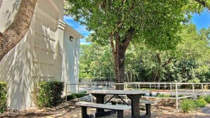 Uma mesa de piquenique em um ambiente semelhante a um parque, com um edifício branco ao fundo.