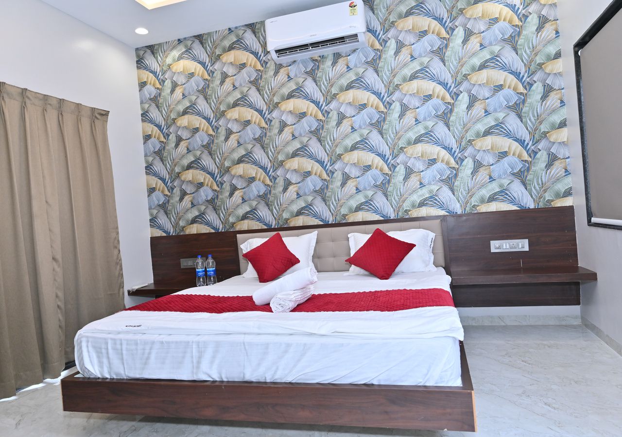Habitación de hotel con cama, cabecera, mesita de noche y aire acondicionado instalado en la pared.