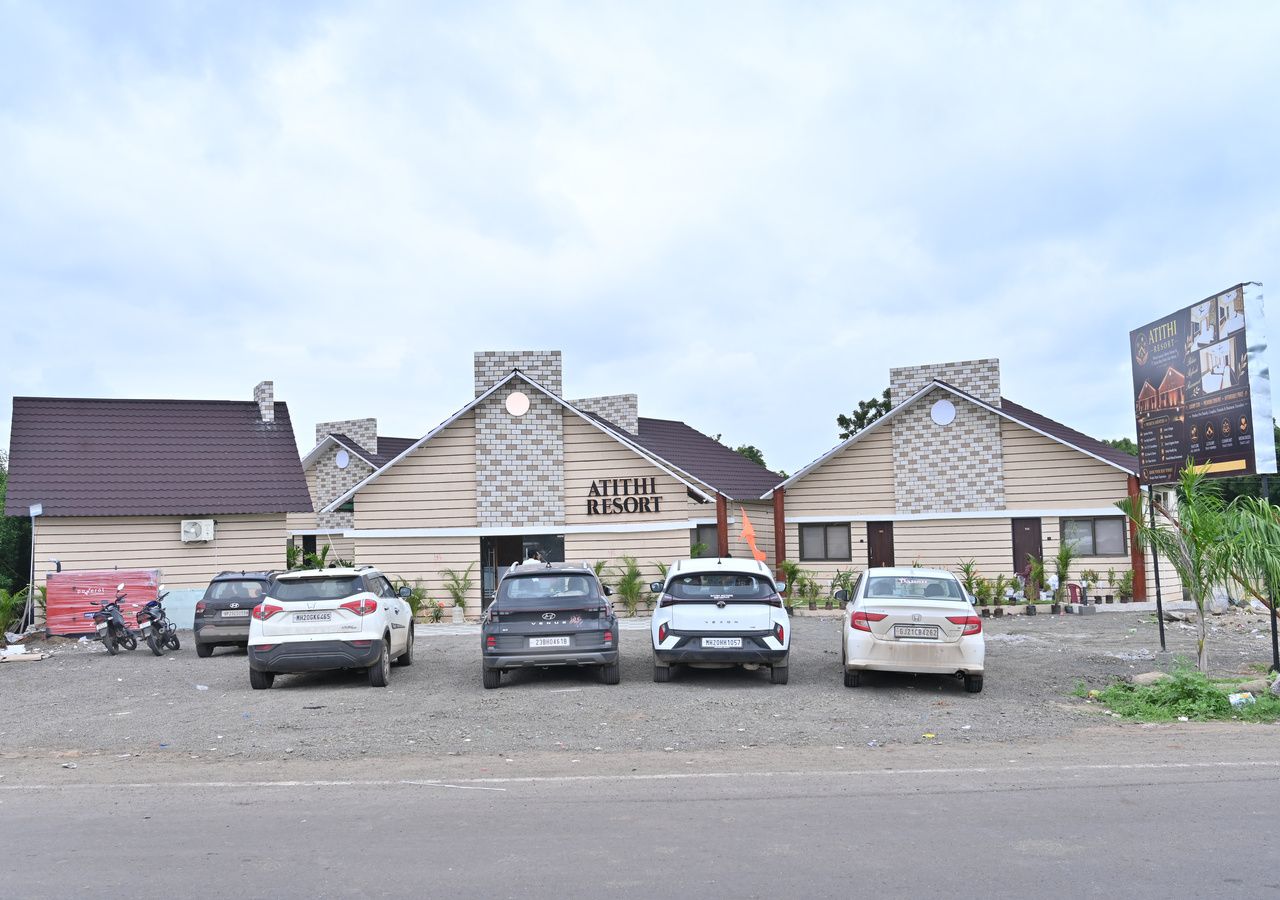Un bâtiment portant l’inscription « Atithi Resort » avec un parking situé devant.