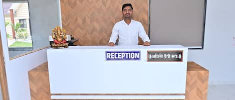 A reception desk with a sign that reads 'RECEPTION' and another in a local language.