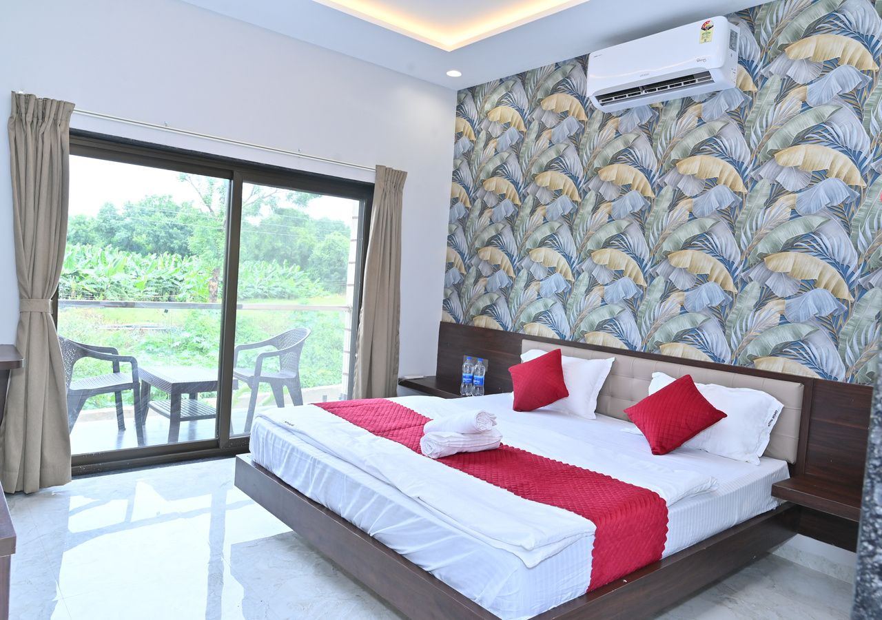A hotel room with a large bed, a view through the glass door, and an air conditioning unit on the wall.