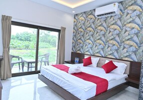 Habitación de hotel con una cama grande, vista a través de la puerta de vidrio y un equipo de aire acondicionado en la pared.