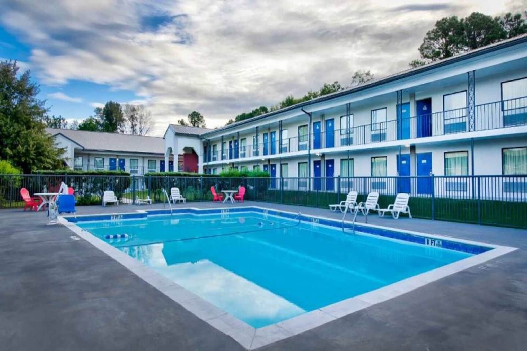 Et motel med swimmingpool, flere altaner og en indhegnet patio med liggestole.