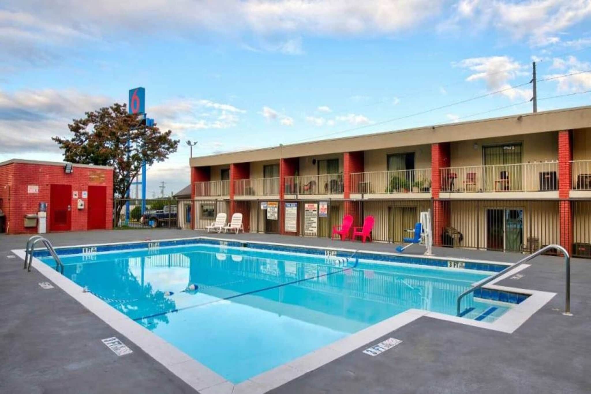 A motel with a swimming pool, a red brick building, and a two-story structure with balconies.