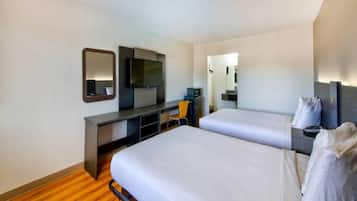 A hotel room with two beds, a desk, a TV, and a mirror.