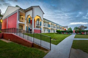 Een hotel met meerdere verdiepingen, een bakstenen gevel, een centrale trap en een verzorgd gazon.