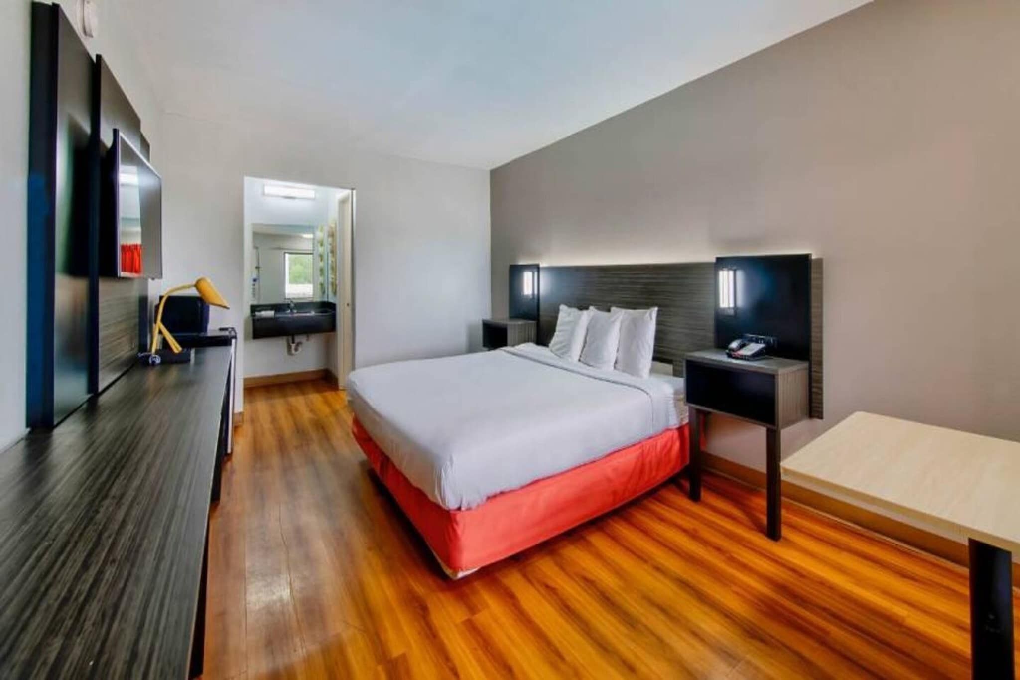 Een moderne hotelkamer met een groot bed, houten vloeren, een bureau en een televisie.