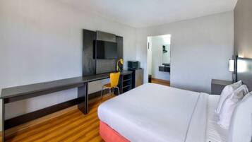 A hotel room with a bed, a desk, a chair, a television, and a mirror.
