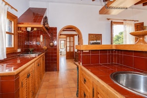 A kitchen with wooden cabinets, a tiled backsplash, and a large sink.