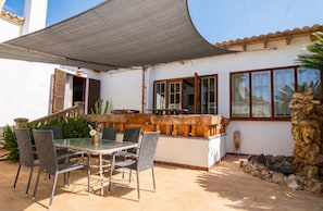 An outdoor patio with a table and chairs, a stone wall, and a shaded area.