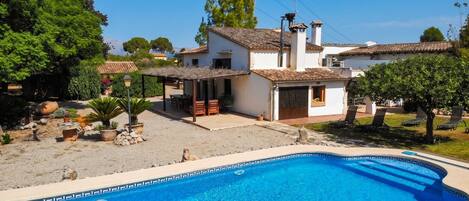Propiedad residencial con piscina, zona de estar al aire libre y jardín.