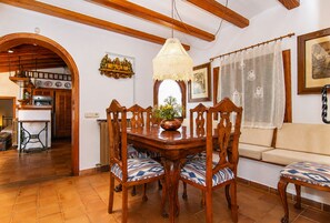 A dining area with a wooden table, chairs, and a hanging light fixture.