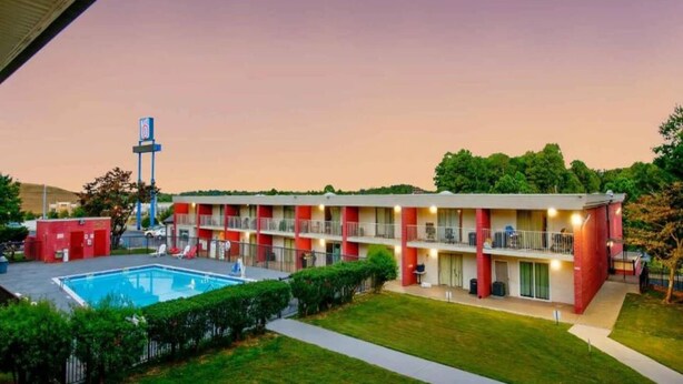 Un motel con piscina, varios balcones y una zona de estacionamiento.