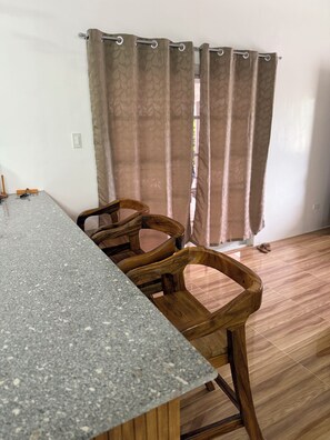 A room with a granite countertop, wooden chairs, a curtain, and a tiled floor. - Casita Nela: Cozy 3BR Private Haven near Tagaytay (Silang)