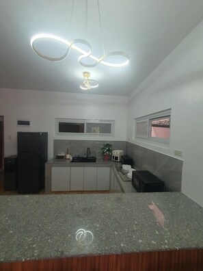 A kitchen with a granite countertop, a refrigerator, a sink, and a window. - Casita Nela: Cozy 3BR Private Haven near Tagaytay (Silang)