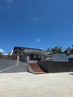 Un edificio moderno con una escalera que conduce a un acceso cubierto, rodeado de una zona de hormigón.