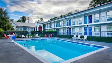 A motel with a swimming pool, multiple rooms, and a fenced patio area.