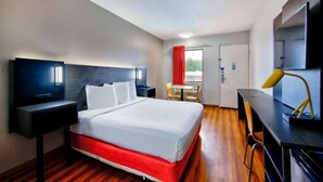 A hotel room with a bed, a desk, a chair, a TV, and a door. - 1 King Bed | Mobility Accessible Tub, Nsmk (Gainesville)