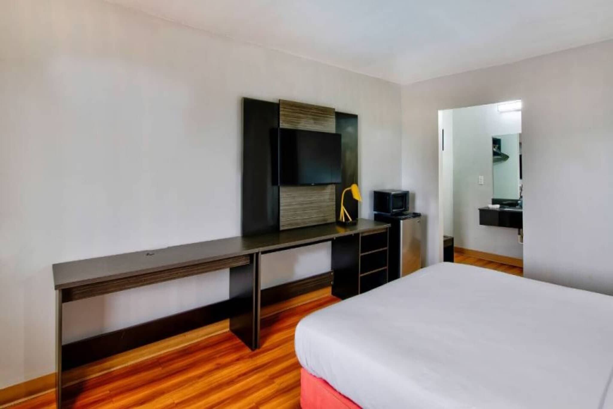 A hotel room with a bed, a desk, a television, and a mirror.