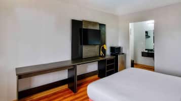 A hotel room with a bed, a desk, a television, and a mirror.