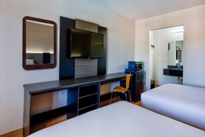 A hotel room with a bed, a desk, a chair, a television, and a mirror. - 2 Full Beds Smoking | Gainesville (Gainesville)